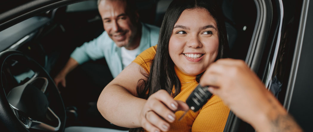 young woman reaching for car keys while sitting in a car